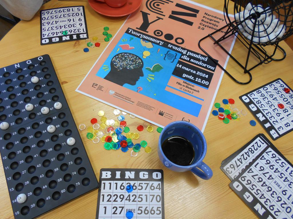 Rozłożone plansze do gry w BINGO i plakat Narodowego Rozwoju Czytelnictwa na stoliku