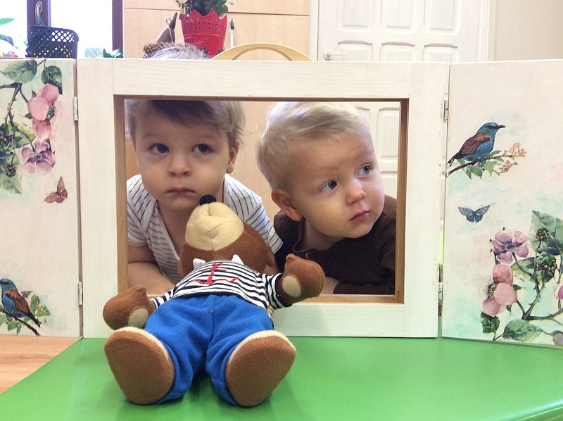 Zdjęcie przedstawia dwoje dzieci, spogladajacych przez okienko teatrzyku.