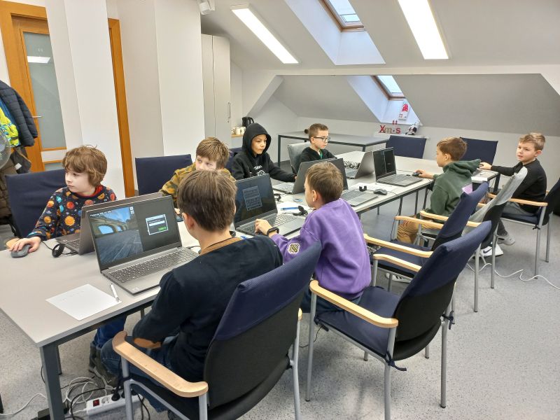 Grupa chłopców siedzi przy komputerach
