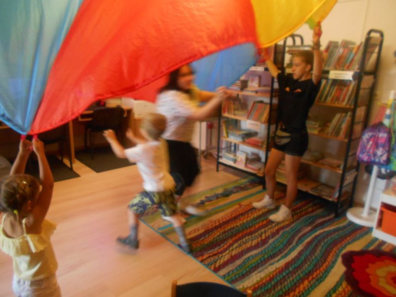 Dzieci bawią się używając kolorowej chusty