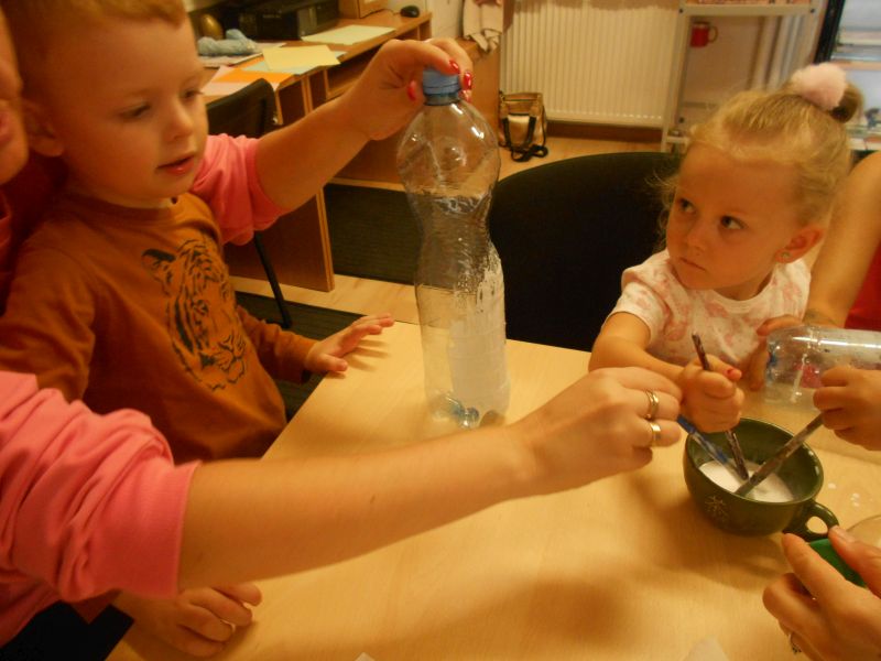 Dziewczynka i chłopczyk ozdabiają butelkę plastikową