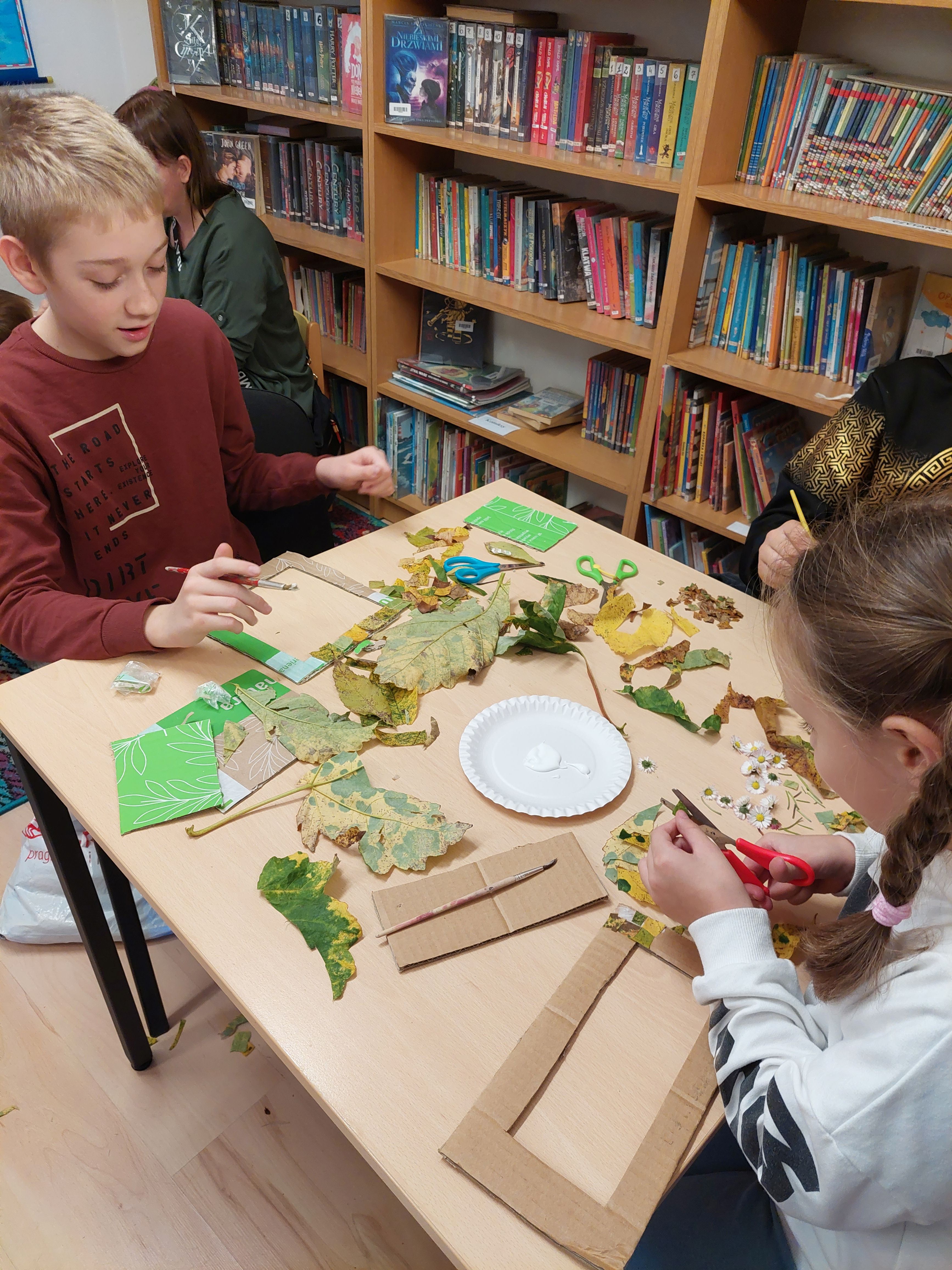 Dzieci oklejają ramki liśćmi 