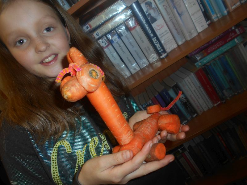 Dziewczynka prezentuje rzeźbę z marchewki - Żyrafa