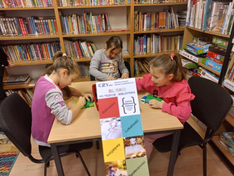 Trzy małe dziewczynki budują z klocków lego