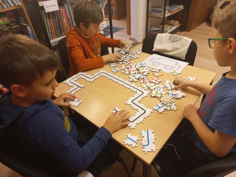Trzech chłopców układa trasę dla ozobotów z dedykowanych im puzzli