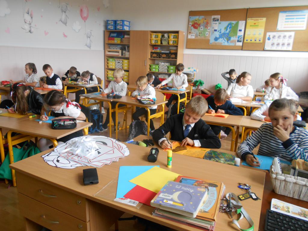 Uczniowie siedzą w ławkach i tworzą książeczkę leporello