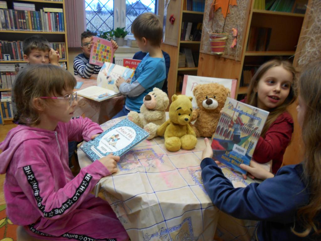 Dziecprzy stolikach oglądają książeczki o misiach